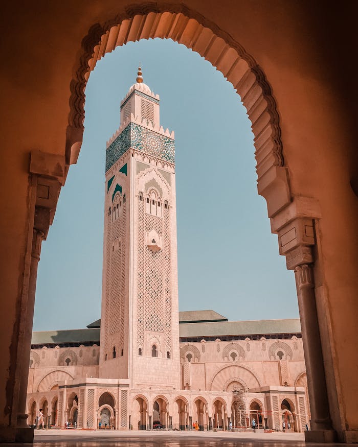 Elegant view of the Hassan II Mosque minaret through an ornate archway in Casablanca, Morocco.